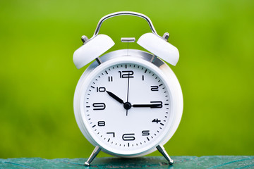 White alarm clock on green background. 