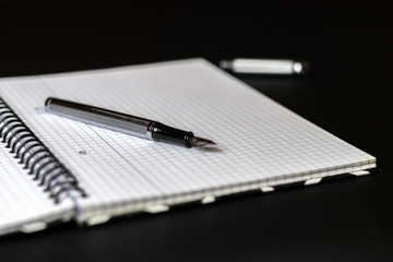 Notebook and pen on a black background