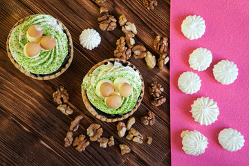 Cake in the form of a basket with mushrooms, peeled walnuts and meringues on the table of pine planks. Natural brown and pink background. View from above