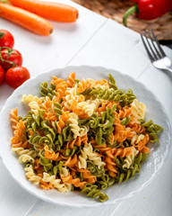 Multicolored pasta with vegetable on wooden background ve vegetables