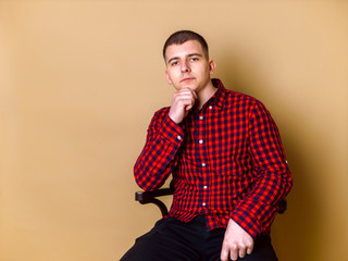 Fototapeta premium Elegant man siting and posing on brown background. Thinking about difficulty of life. Concept for blog, lifestyle