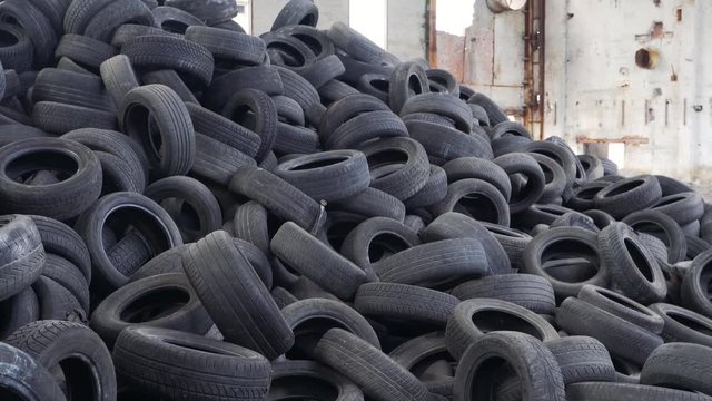 Pile of old tires stacked in junkyard panned up from base to top.