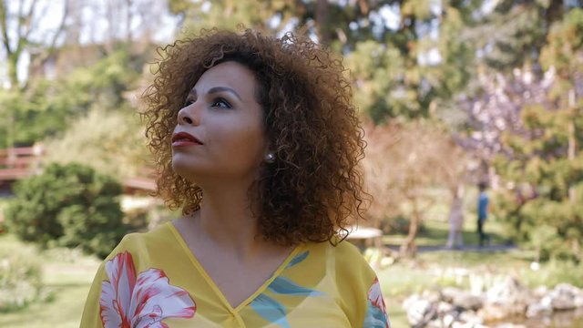 Sch&ouml;ne  arabische Frau schaut in die Kamera und um sich herum. Nahaufnahme im Park mit einem unscharfen Hintergrund