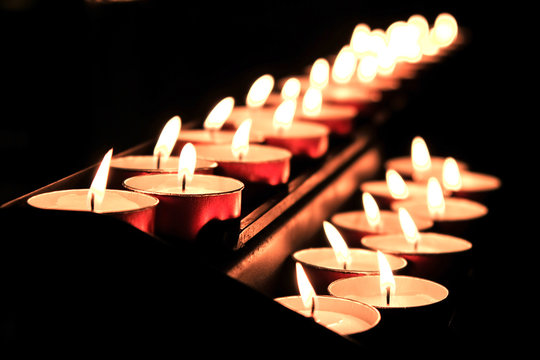 Gruppo di lumini e candele accese al buio in chiesa