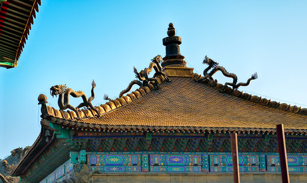 Scary dragons on ancient tiled, golden roof on Buddhist colorful temple in Chengde, China.