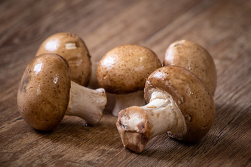 Fresh whole brown champignon mushrooms on vintage wooden table