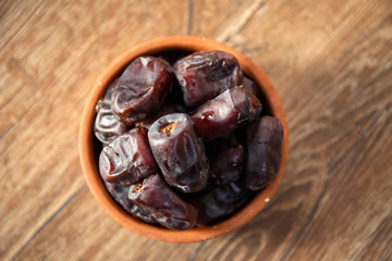 Fresh organic dates fruits in a clay bowl on wooden table