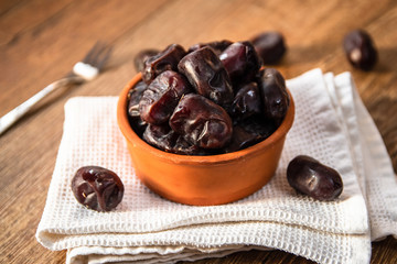 Fresh organic dates fruits in a clay bowl on wooden table