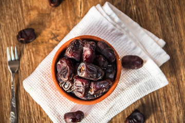 Fresh organic dates fruits in a clay bowl on wooden table