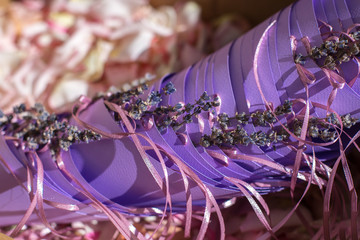 box with purple bags and rose petals to be showered on newlyweds. Event decoration with fresh flowers