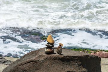 Small stones sculpture resembling two people  in front of the sea, on a rocky region, in Florianopolis, Brazil.