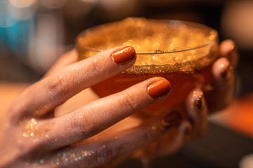 Luxury rich cocktail in golden colours and stardust falling on it. Golden drink.