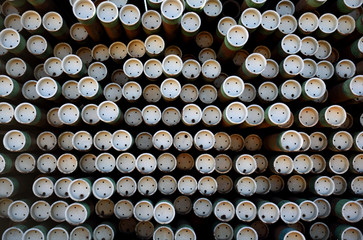 Close up view of a large rack and rows of stacked oil and gas industry iron metal drilling pipes
