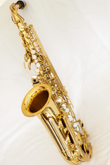 A brass alto saxophone on white background with pearl keys