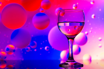 transparent glasses with water and oily drops on colorful background 