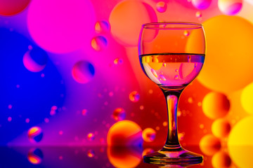 transparent glasses with water and oily drops on colorful background 