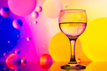 transparent glasses with water and oily drops on colorful background 