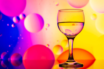 transparent glasses with water and oily drops on colorful background 