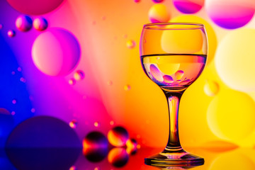 transparent glasses with water and oily drops on colorful background 