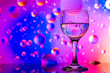 transparent glasses with water and oily drops on colorful background 