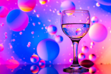 transparent glasses with water and oily drops on colorful background 