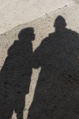 Shadows of a father and son on a rough concrete street