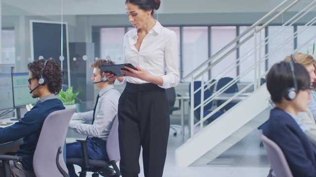 Beautiful Female Manager is Walking Pass Her Customer Service Operator Colleagues and Supervise Their Work. Diverse and Motivated Call Center People Work on Computers and Wearing Headsets.