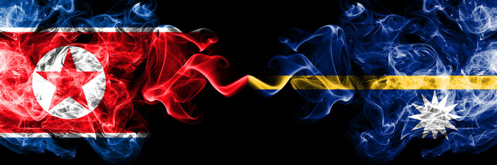 North Korea vs Nauru smoky mystic flags placed side by side. Thick colored silky smoke flags of North Korea and Nauru.