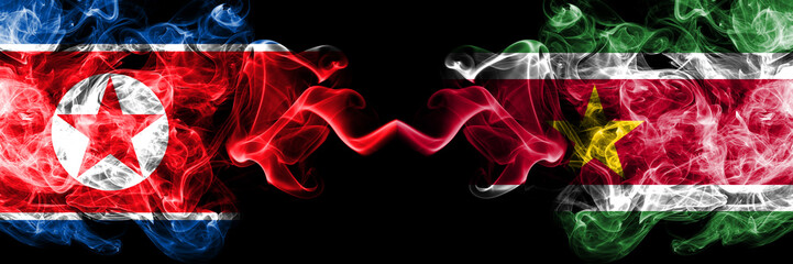 North Korea vs Suriname, Surinamese smoky mystic flags placed side by side. Thick colored silky smoke flags of North Korea and Suriname, Surinamese.