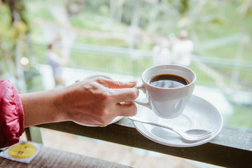 Woman hand holding a cup of hot Luwak coffee, one of the most expensive coffee in the world in the coffee shop in Bali, Indonesia.