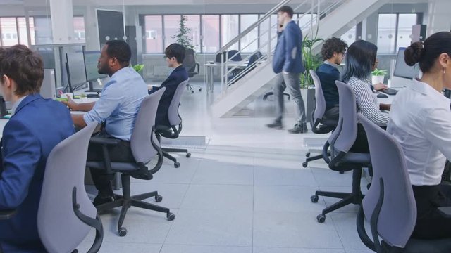 Diverse Team of Business Managers and Specialists Work on Desktop Computers with Two Rows of Tables Side by Side. Young and Motivated Business people in Modern Open Office.