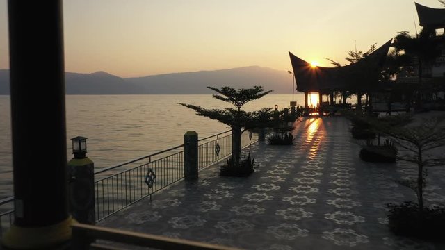 Drone fly-through footage under a pergola at a waterfront resort on Lake Toba in North Sumatra, Indonesia at sunrise.