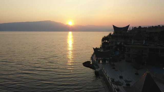 Drone flyover of waterfront resorts on Samosir Island on Lake Toba in North Sumatra, Indonesia at sunrise.