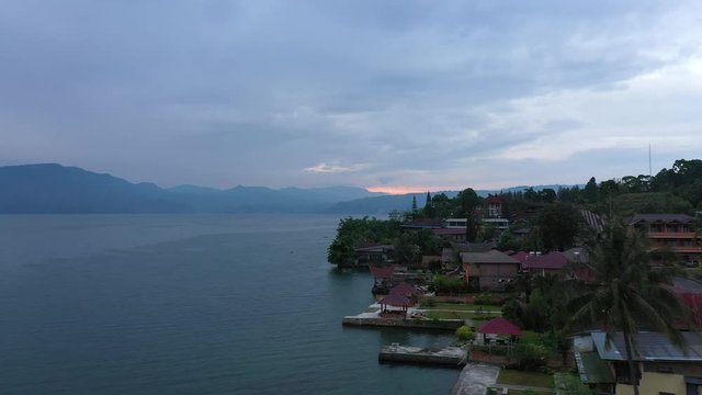 Drone flyover footage of waterfront resorts on Samosir Island on Lake Toba in North Sumatra, Indonesia at sunrise.