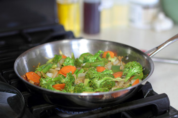 Stir fried vegetables cooking in a stainless steel pan.