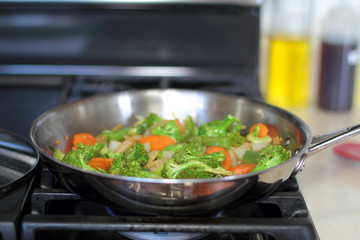 Stir fried vegetables cooking in a stainless steel pan.