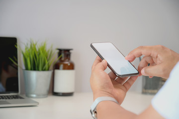 Young businessman holding smartphone at a workspace