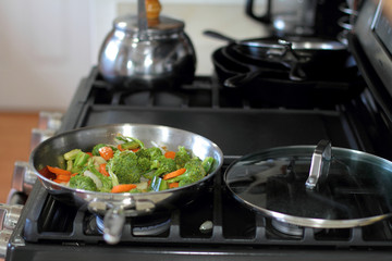 Stir fried vegetables cooking in a stainless steel pan.
