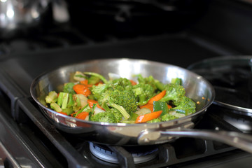 Stir fried vegetables cooking in a stainless steel pan.