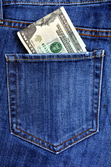 Paper banknotes of American dollars lie on the blue worn jeans.