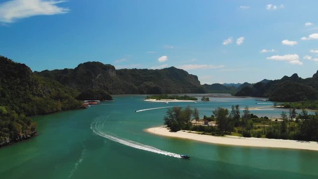 Slow motion drone video of three tour boats sailing out near the Tanjung Rhu Beach in Langkawi