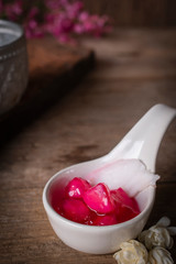 Thapthim krop, mock pomegranate seeds in coconut and syrup in the white spoon bowl on the wood table there are flower and water bowl placed around.