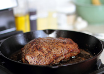 Tri-tip roast in a cast iron pan resting on the oven.
