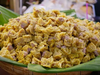 A bunch of pork streamed dumplings on a bannana leaf in a bamboo tray for sale - Thai Kanom Jeeb