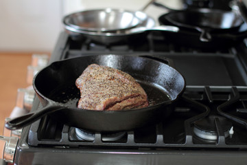 Tri-tip roast in a cast iron pan resting on the oven.