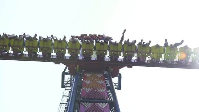 People riding on extreme attraction in amusement park. Happy friends having fun on thrilling roller coaster ride in amusement park
