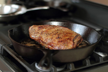 Tri-tip roast in a cast iron pan resting on the oven.