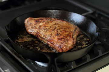 Tri-tip roast in a cast iron pan resting on the oven.