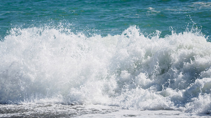 Waves and splashes of water against the sea on a sunny summer day