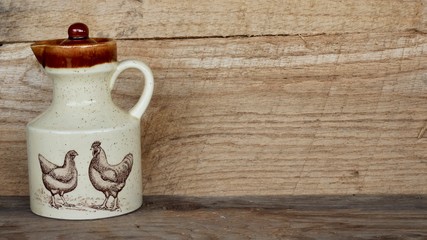 creamer pitcher with roosters on wood background